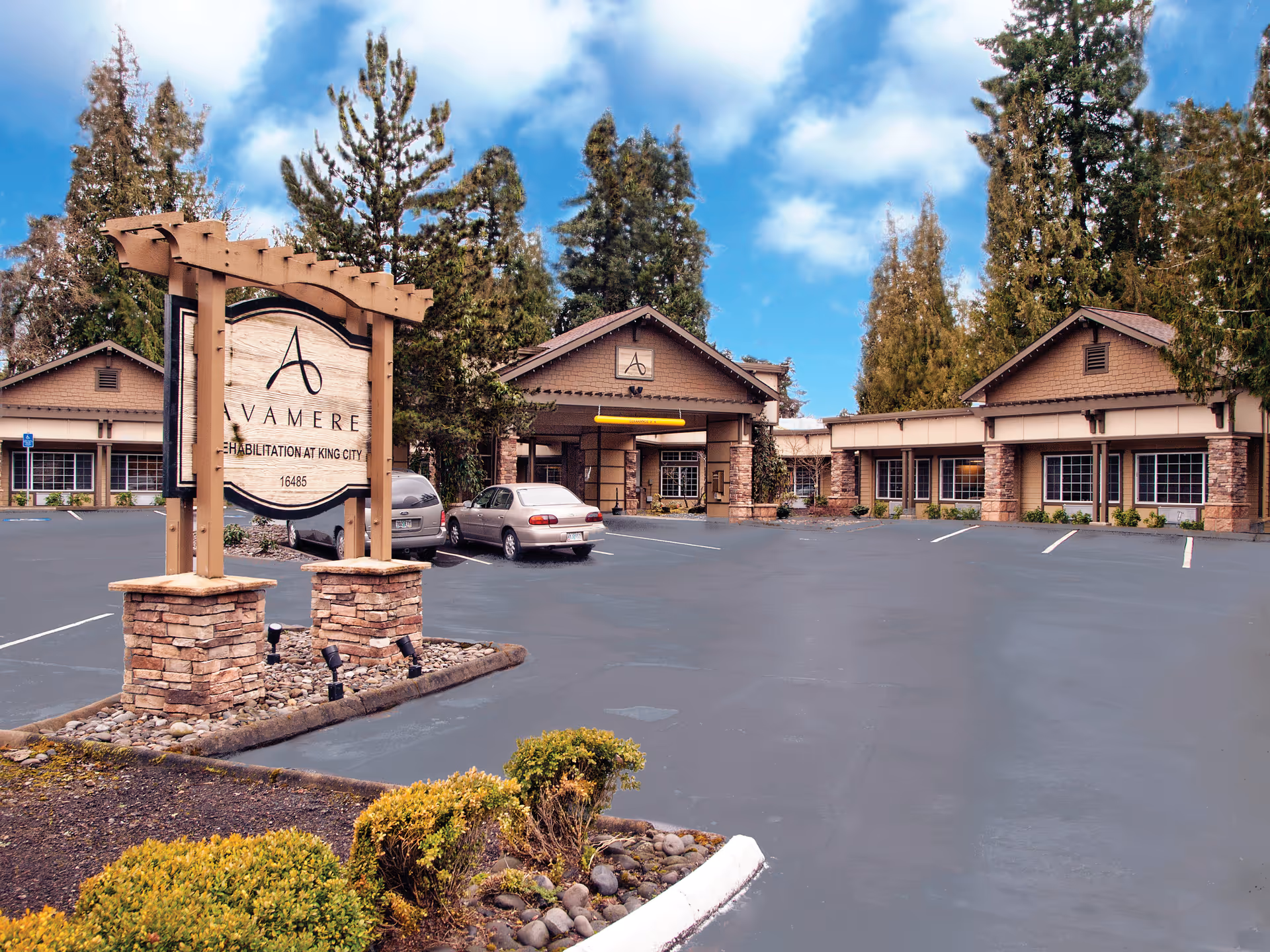 Front exterior of Avamere Rehabilitation of King City showing the entrance, parking lot, and a wooden sign in the foreground.