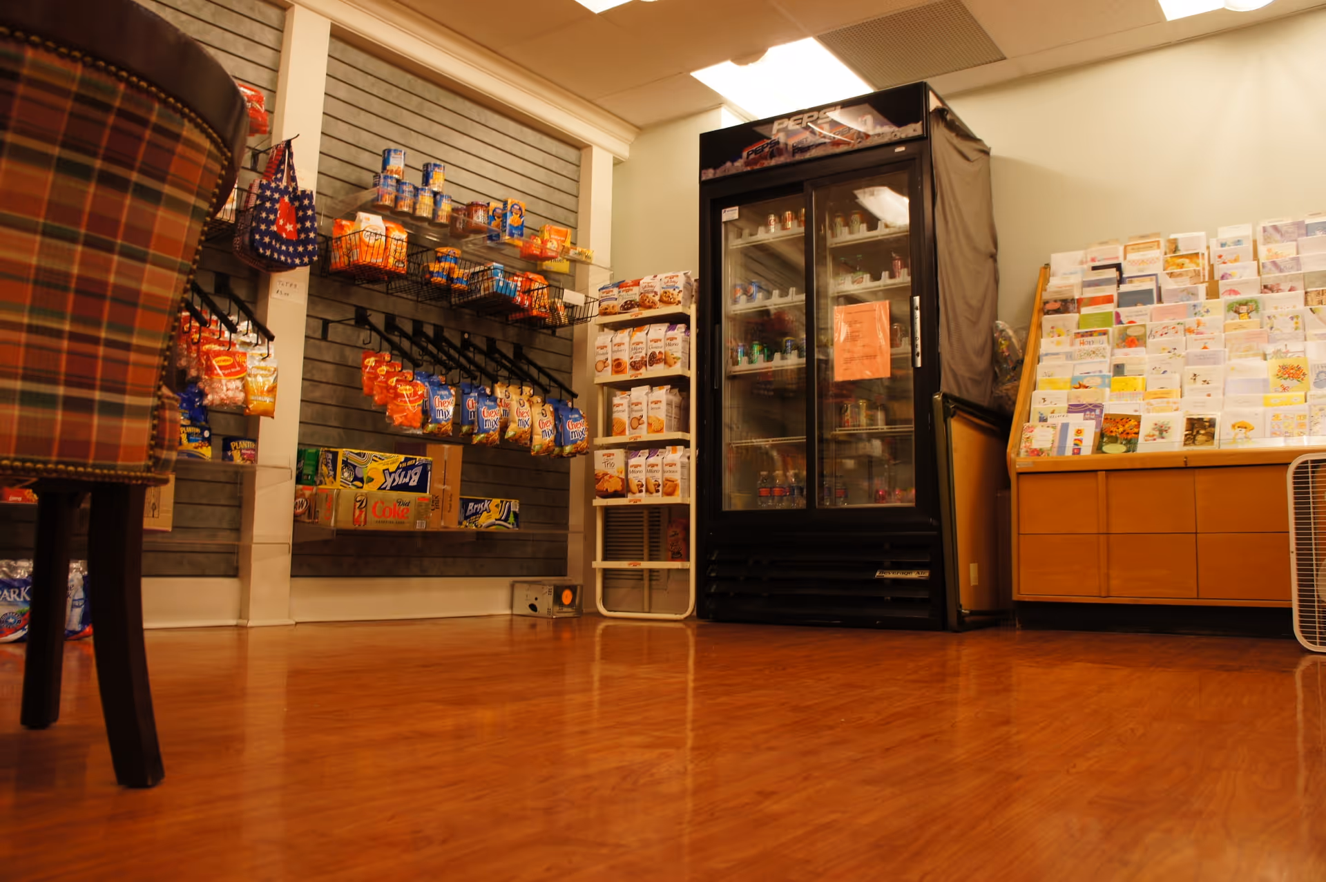 Interior shop area with snack displays, a refrigerated beverage cooler, and a greeting card rack.