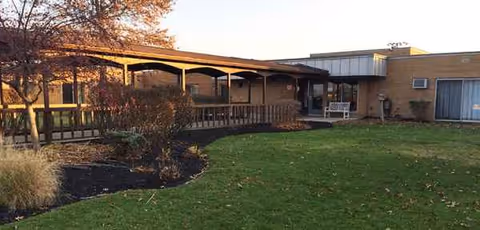 Carington Park exterior of a senior living facility with a covered porch, railing, and lawn.