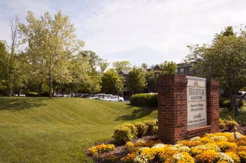 Brick entrance sign for The Rivers at Maryland Farms with blooming flowers and manicured lawn.
