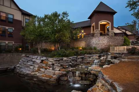 Evening exterior view of Danberry at Inverness with stone waterfall and entrance tower.