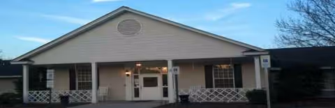Front view of The Magnolia senior facility entrance with double doors and a covered porch.