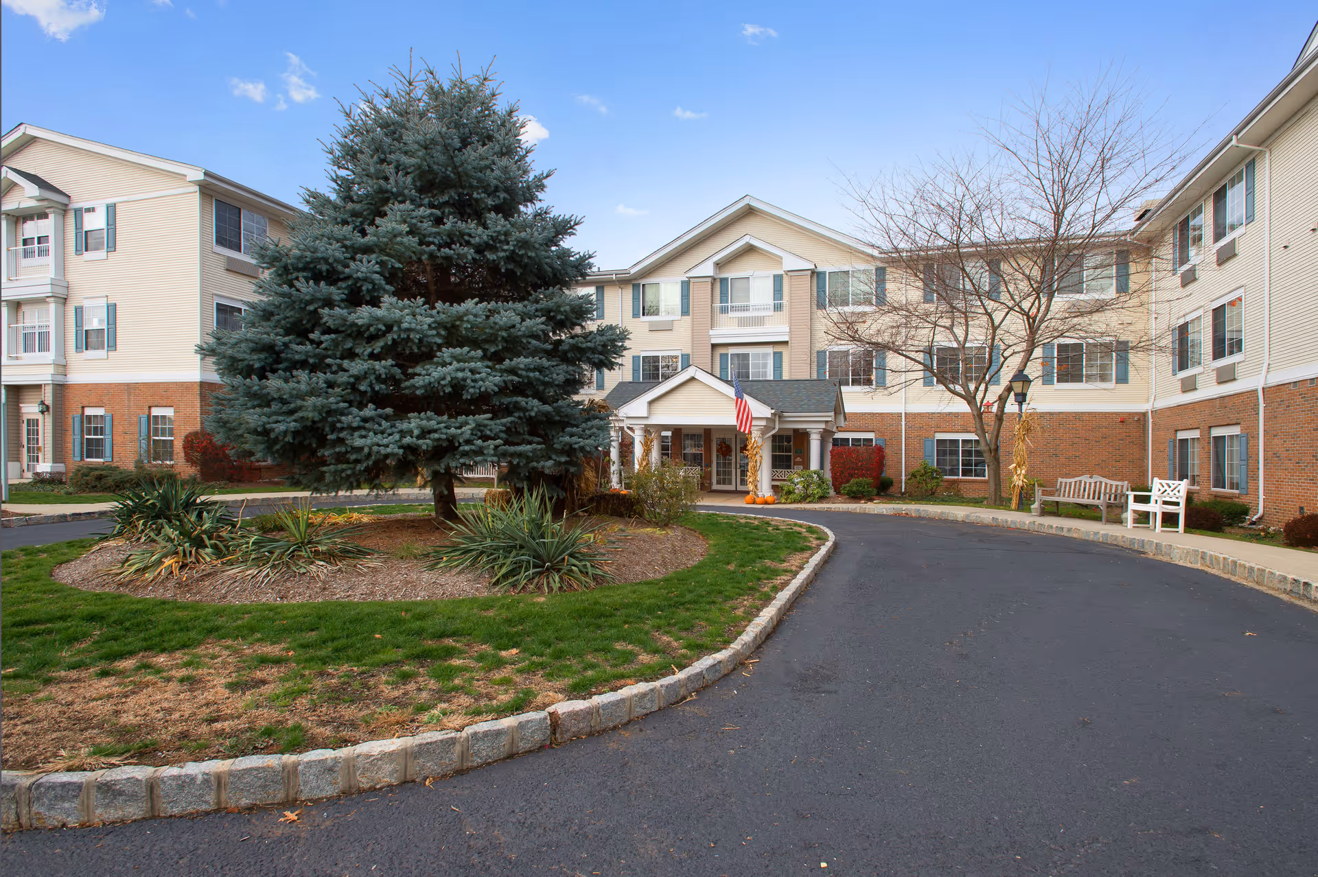 Exterior view of Kinship Pointe at Wayne with curved driveway, trees, and landscaped entrance.