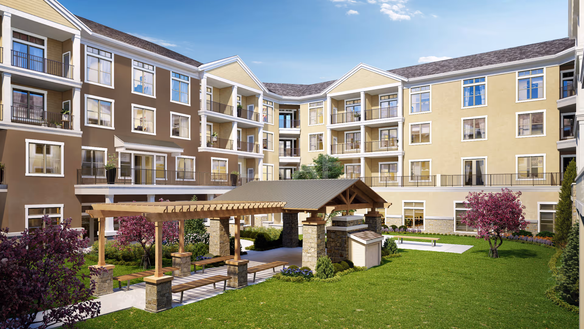 Sunlit courtyard with a covered pergola, benches, green lawn and a surrounding multi-story senior living building.