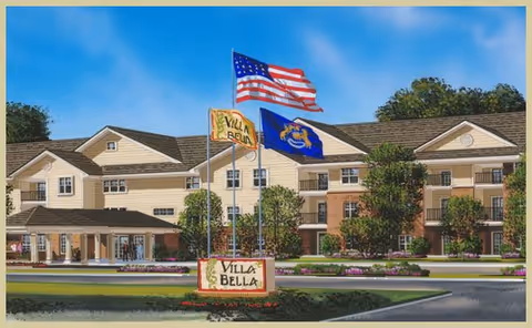 Exterior view of Villa Bella senior living facility with flags and landscaped entrance.