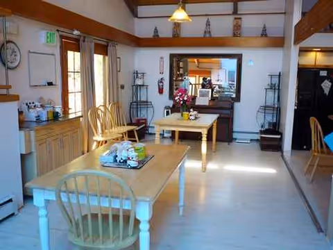 Sunlit dining room at Harbor View Manor with wooden tables, chairs, and decor.