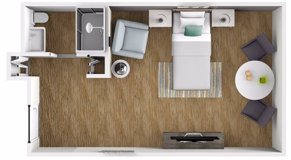Top-down view of a small studio apartment floor plan featuring a single bed with two nightstands, a small sitting area with two chairs and a round table, a separate armchair with a side table, a bathroom with a shower, toilet, and sink, and a kitchenette area near the entrance.