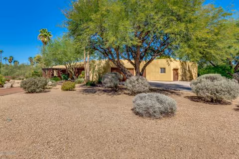 Beige assisted living facility exterior with desert landscaping and trees.