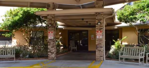 Entrance to The Reserve at Citrus with stone columns, benches, and landscaping under a covered walkway.