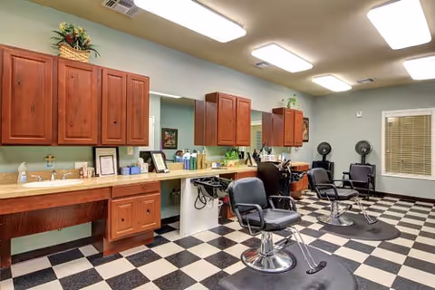 Salon-style room with barber chairs, mirrors, wooden cabinetry and a black-and-white checkered floor.