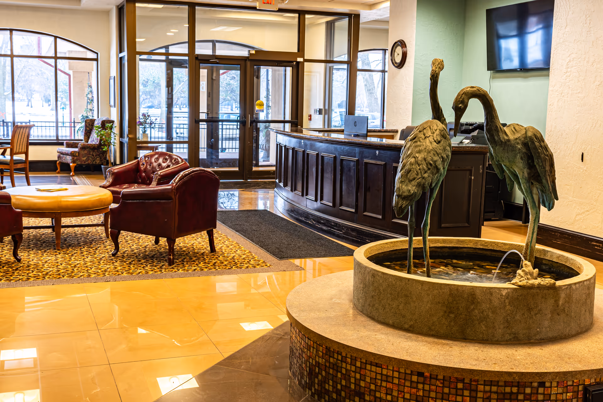 Lobby with seating area, a reception desk, and a decorative fountain featuring bird sculptures.