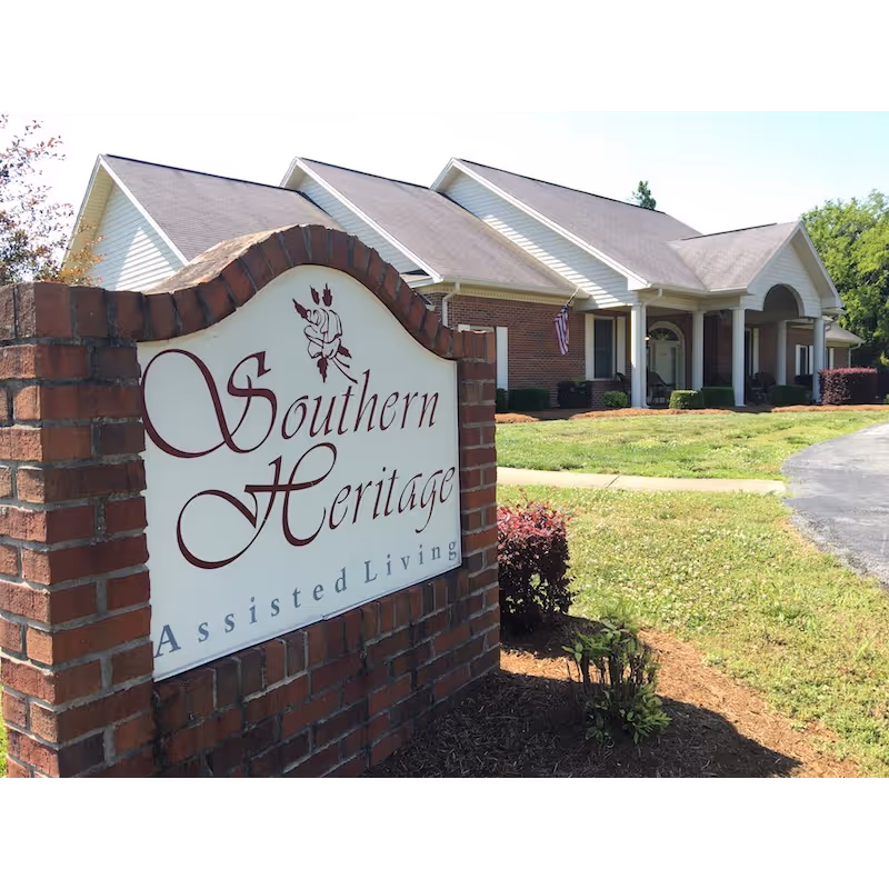 Brick entrance sign that reads 'Southern Heritage Assisted Living' in front of a single-story assisted living building with columns and a lawn.