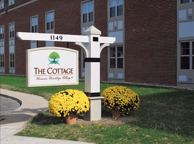 Exterior view of The Cottage sign in front of a brick Wexner Heritage Village building.