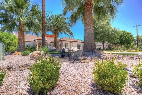 Front exterior of a senior living facility with palm trees and desert landscaping.