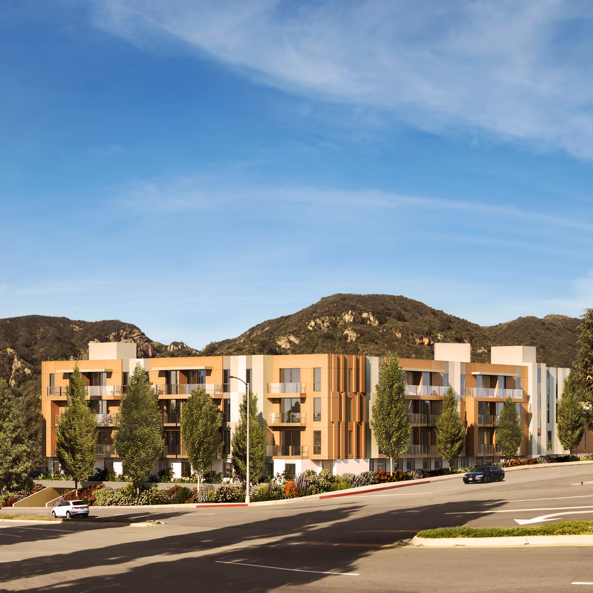 Exterior view of a modern, multi-story senior living facility named Ciela Senior Living, surrounded by trees and landscaping, with hills in the background under a clear blue sky.
