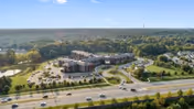 Aerial view of The Summit senior living campus with buildings, parking lots, surrounding roads and wooded landscape.