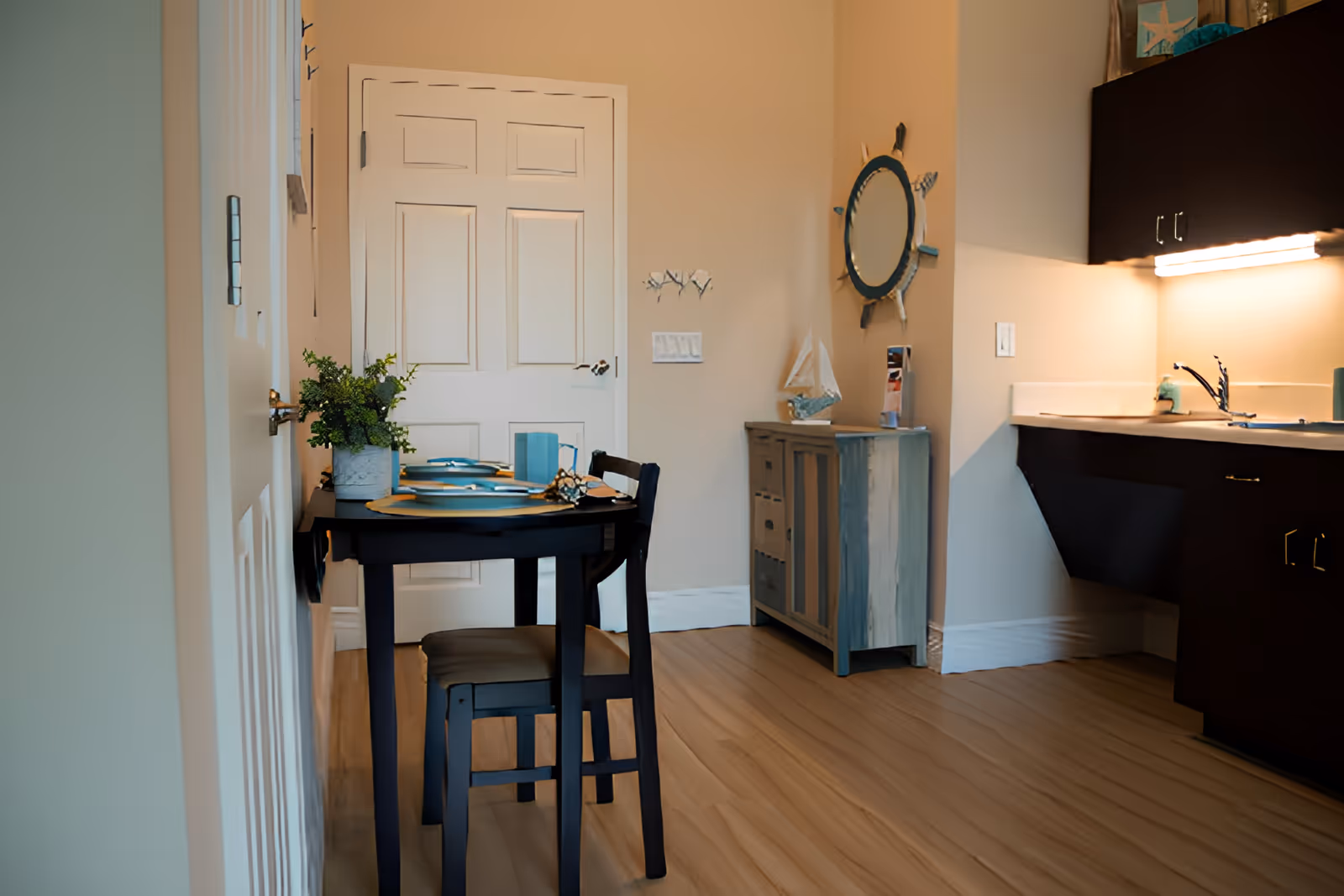 Small dining nook with a set two-person table next to a kitchenette and cabinetry.