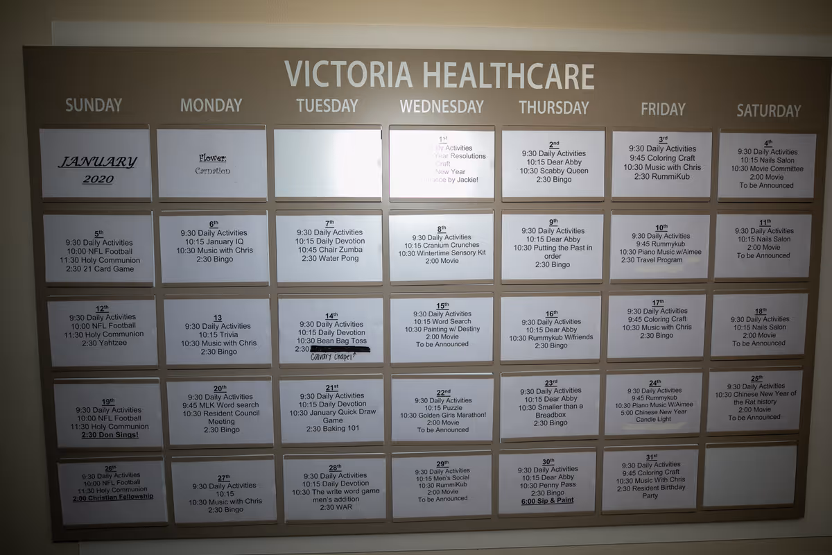 Wall-mounted monthly activity calendar board for Victoria Healthcare showing daily scheduled events for January 2020.