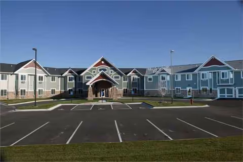 Front exterior of Grand Meadows Senior Living: colorful townhome-style buildings and a parking lot.