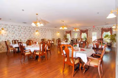 Bright dining room with floral wallpaper, chandeliers, and arranged tables.
