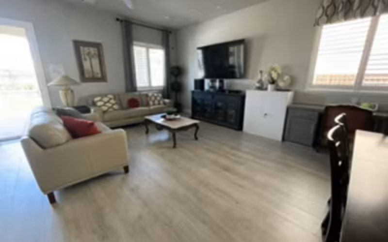 Open, bright living room with two sofas, a coffee table, and a wall-mounted TV.