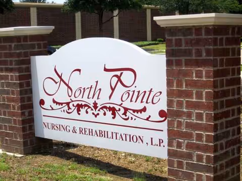 White sign with decorative red text reading North Pointe Nursing & Rehabilitation between brick pillars.