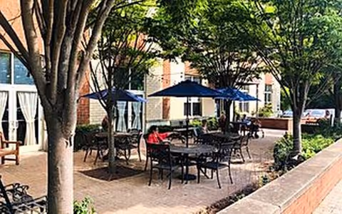 Outdoor courtyard with tables and blue umbrellas at a senior living facility