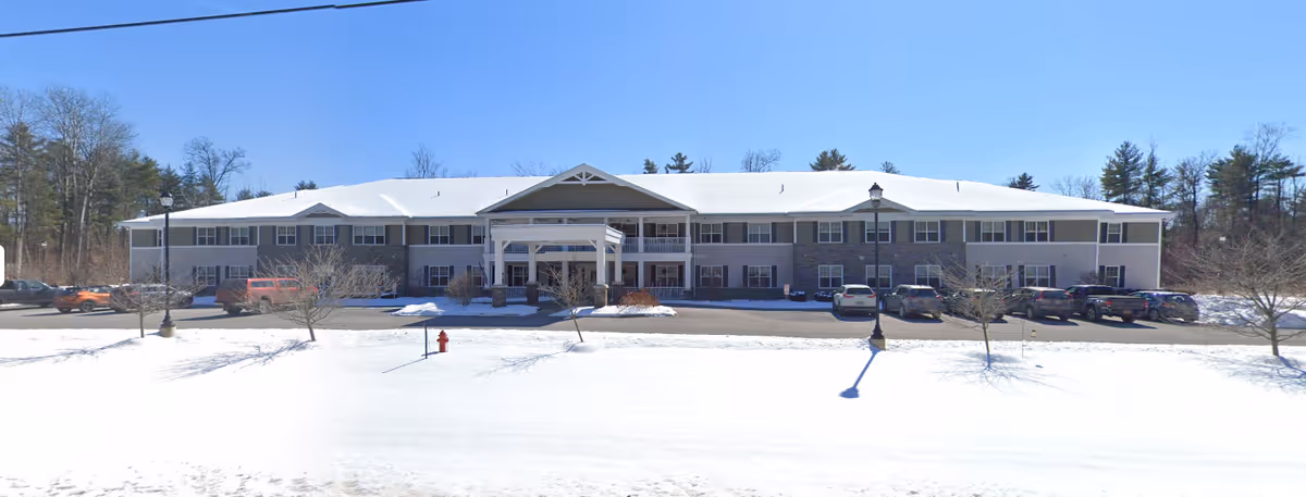 Front exterior view of a two-story senior living facility building named Home of the Good Shepherd – Moreau, surrounded by snow-covered ground and trees, with several parked cars in front.
