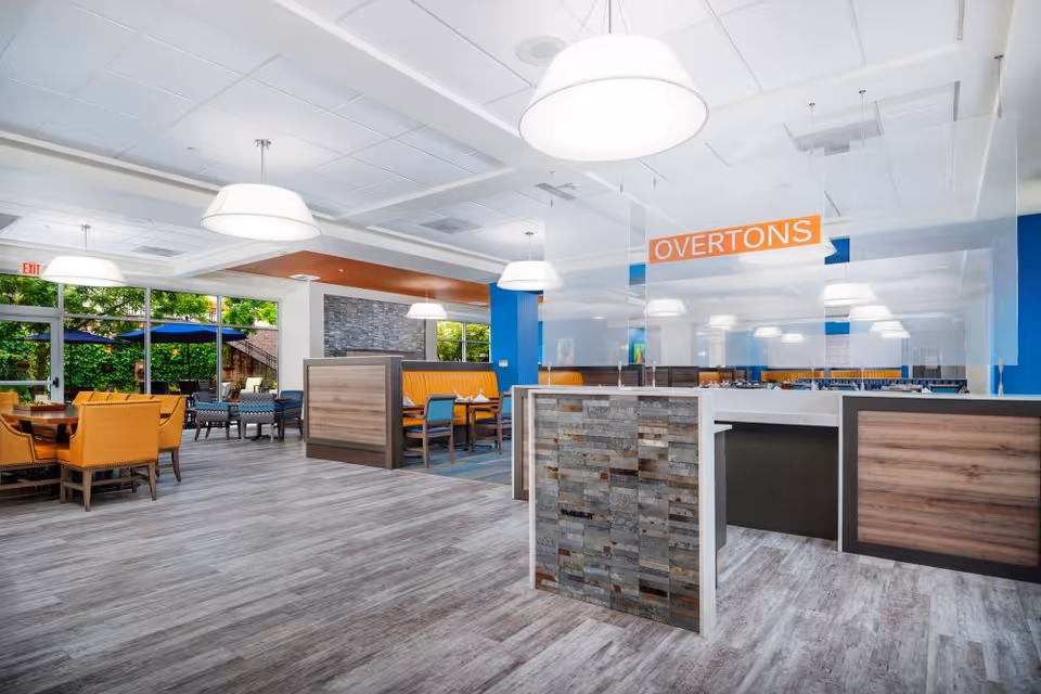Bright modern dining area with booths, tables, pendant lights and a sign reading "OVERTONS".