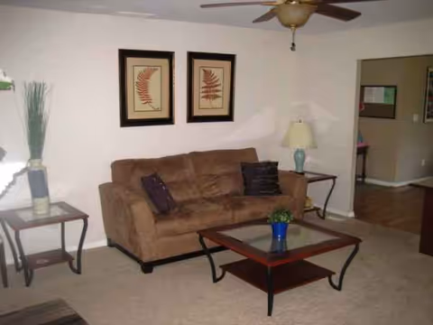 Cozy living room with brown sofa, coffee table, lamps, and wall art.