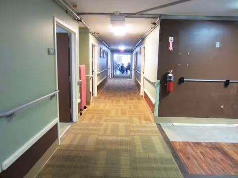 Interior hallway of a senior living center with doors and handrails.