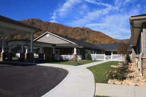 Front view of Maggie Valley Nursing and Rehabilitation facility with curved driveway and mountain backdrop.