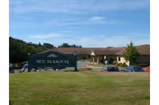 Exterior view of Summit Place senior living showing a large front sign, brick building, and cars.