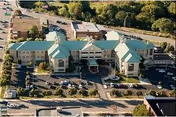Aerial view of the Gino J Merli Veterans Center, a large multi-wing building with green roofs surrounded by trees, parking lots, and roads.