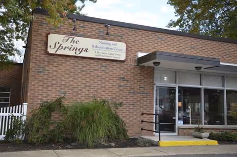 Exterior brick facade of The Springs nursing and rehabilitation center with glass entrance.