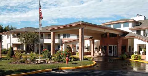 Exterior view of Holiday Briarcrest Estates showing a covered entrance, flagpole, and landscaped grounds.