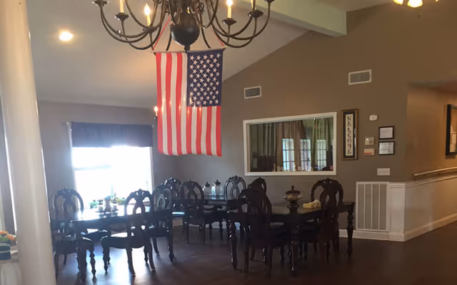 Dining room with multiple dark wooden tables and chairs, a chandelier, and an American flag hanging from the ceiling.