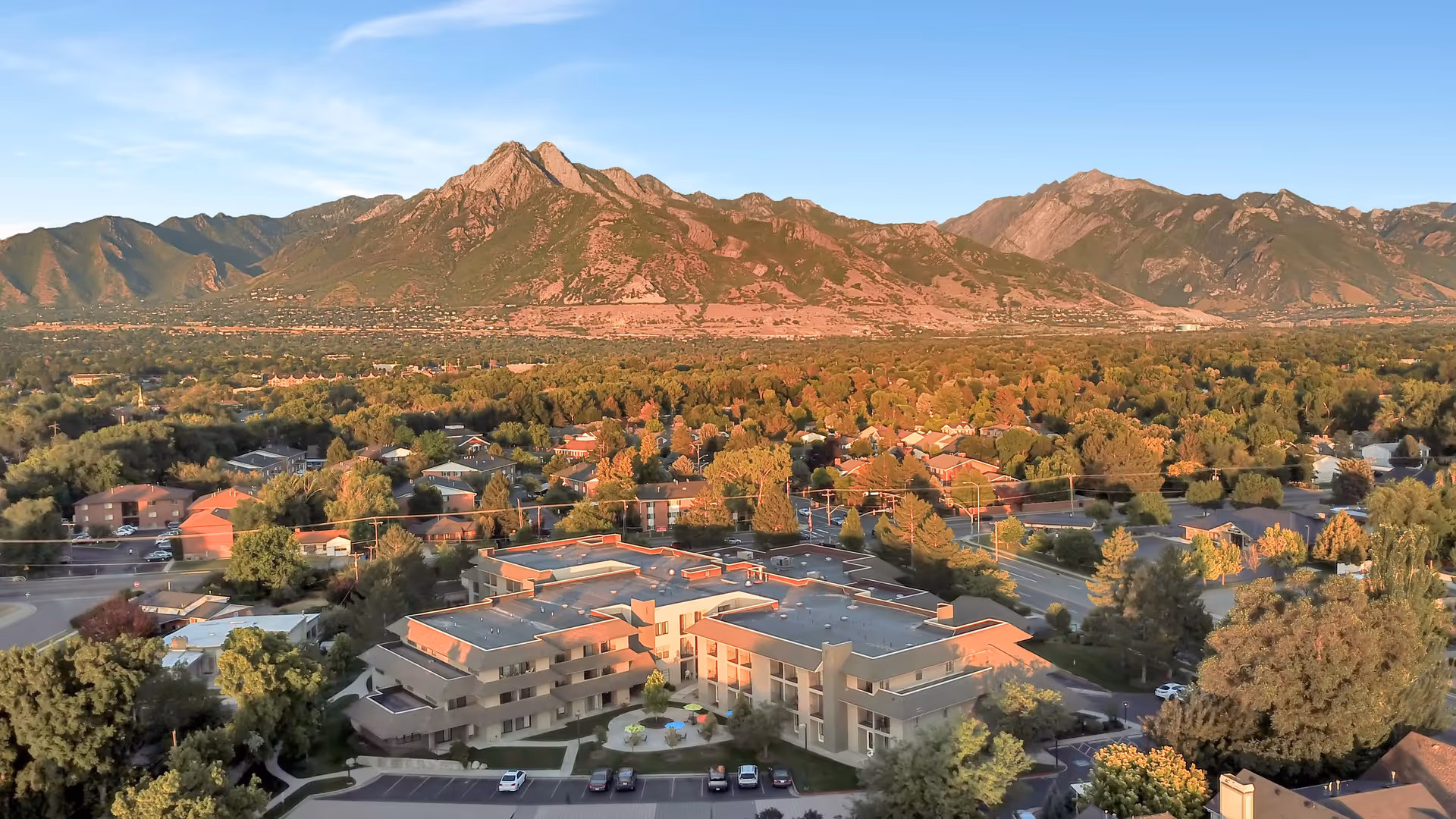 Aerial view of the Cottonwood Creek senior living complex surrounded by trees with mountains in the background.