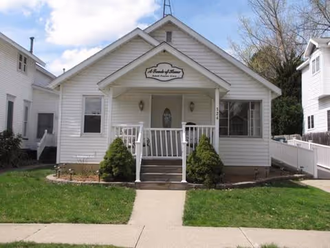 White, single-story senior living facility with a small porch and landscaped entry.