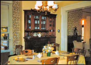 A vintage dining room with round tables, chairs, and a dark wooden china cabinet.