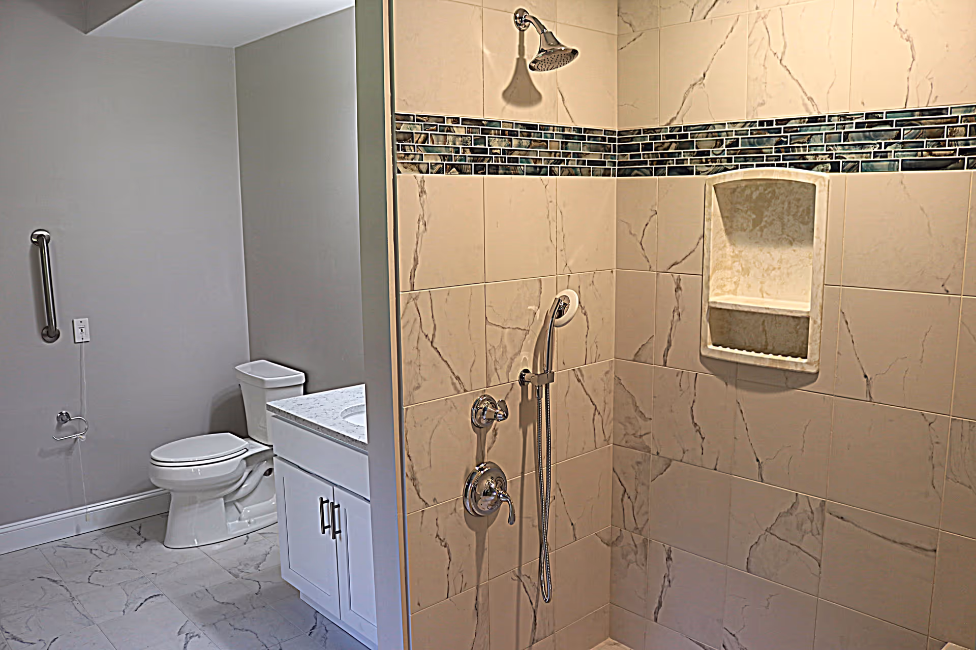 Tiled bathroom with a walk-in shower featuring a handheld showerhead, a toilet, and a vanity.