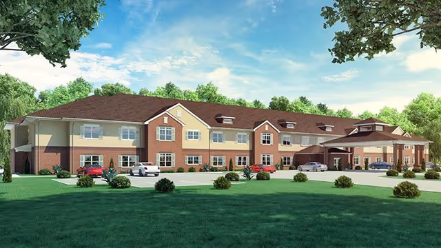 Exterior view of a two-story senior living facility building with a covered entrance, surrounded by green grass and trees under a partly cloudy sky.