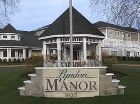 Front entrance of a senior living facility with a stone sign reading Lynden Manor.