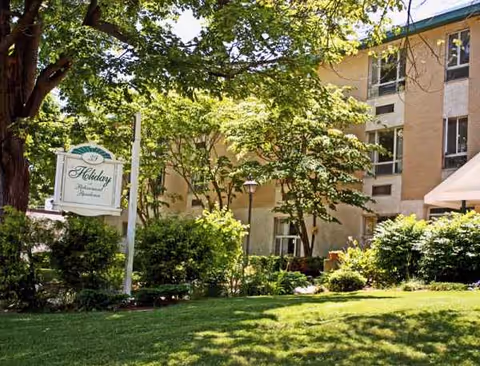 Exterior view of Holiday Retirement building with green lawn and trees.