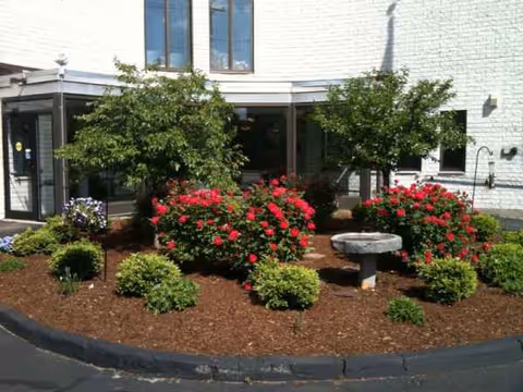 Front entrance of Fenno House with landscaped flower beds and shrubs.