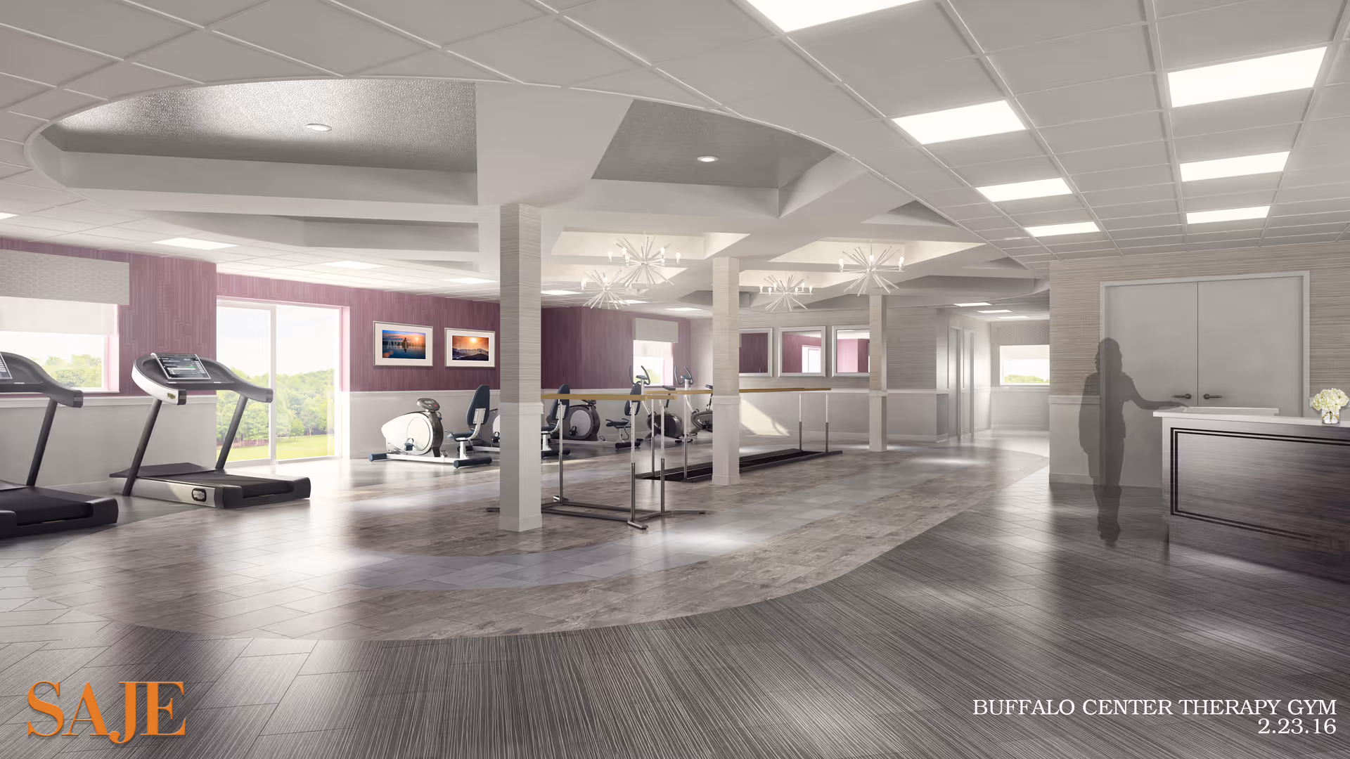 A spacious and well-lit therapy gym with exercise equipment including treadmills and stationary bikes. The room features large windows with a view of greenery outside, modern ceiling lights, and a reception desk on the right side. The floor has a mix of wood and tile patterns, and there are framed pictures on the walls.