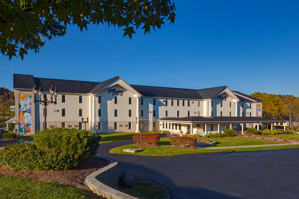 Front exterior of a large three-story senior living building labeled Easy Living with landscaped grounds and a covered entrance.