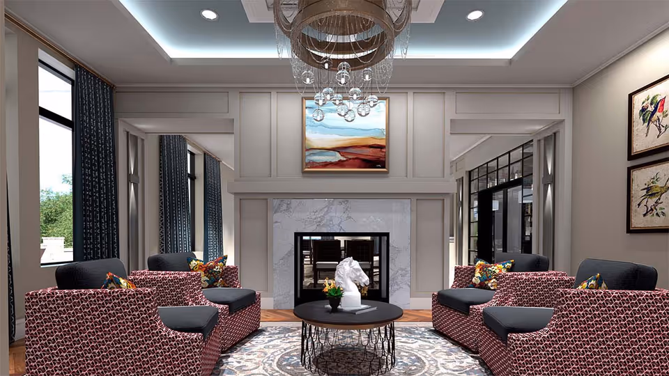 A modern senior living facility lounge area with four patterned armchairs arranged around a round black coffee table. The coffee table has a white horse head sculpture and a small plant. The room features a white marble fireplace with a colorful abstract painting above it, large windows with dark curtains, and framed bird artwork on the wall. A decorative chandelier hangs from the ceiling.