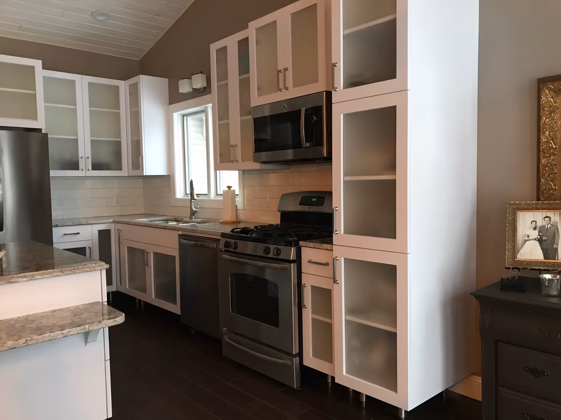 Modern kitchen with white cabinets, stainless steel appliances, and granite countertops.