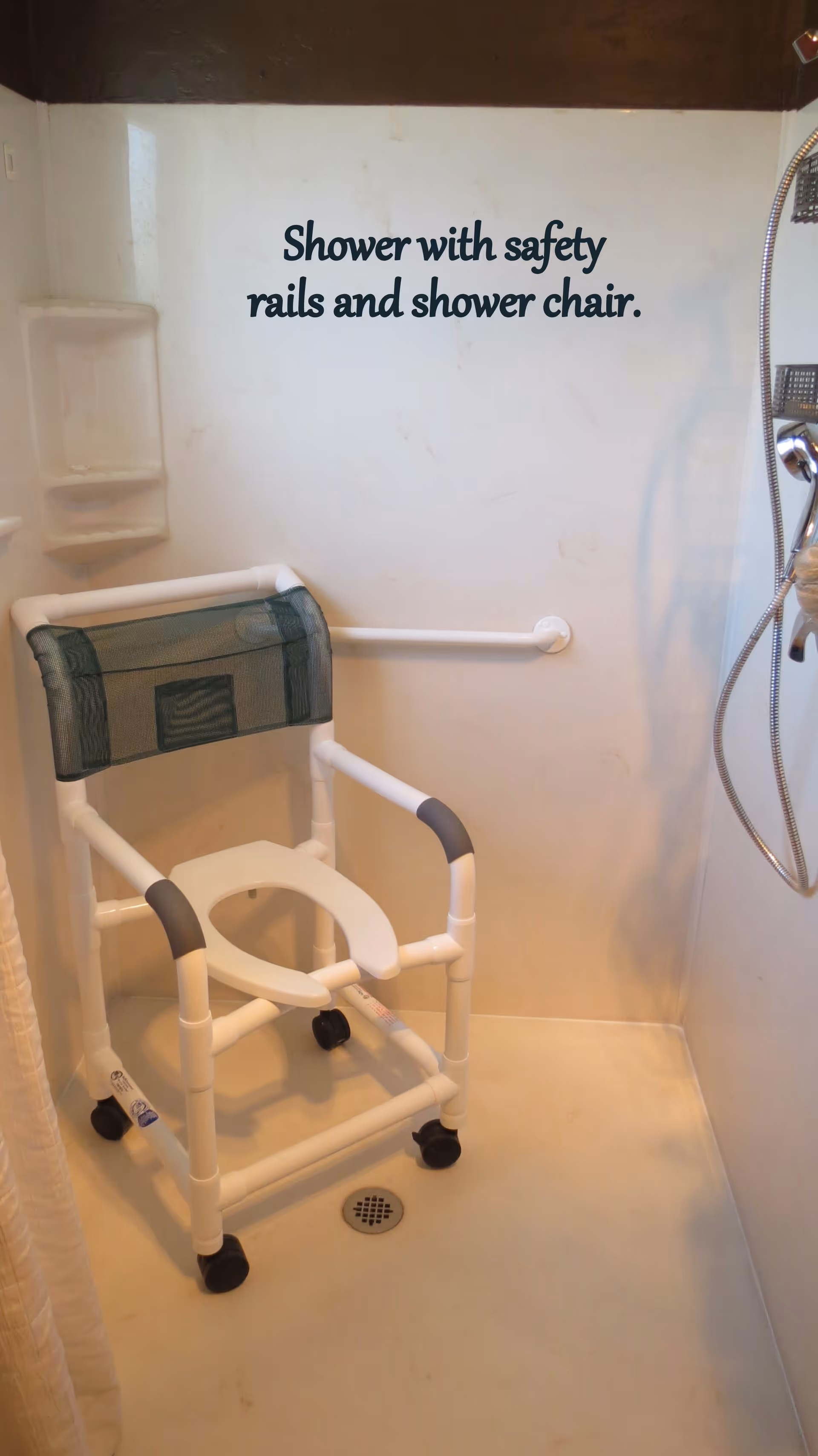 Shower stall featuring a mobile shower chair, a horizontal grab bar, handheld showerhead, and wall text reading 'Shower with safety rails and shower chair.'